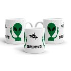 Fehér kerámia bögre béke jelet mutató zöld alien földönkívüli fejel, repülő csészealj UFO sziluettel és fekete believe felirattal.