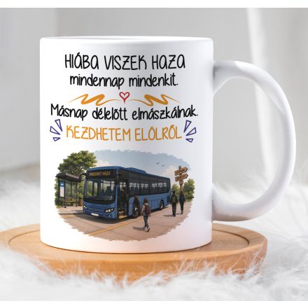 Férfi kézben tartott fehér kerámia bögre kék autóbusz grafikával és vicces sofőr felirattal