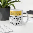 Sárga sávos music feliratú fehér kerámia bögre fekete hangjegyekkel, kottavonalakkal és basszuskulcs grafikájával.